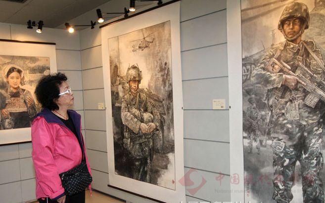 观众在一副展现军人戎马生涯的人物画前驻足观看.jpg